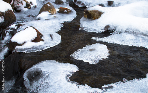 Patches of ice cover a small stream and cling to rocks in the Tongariro National Park, New Zealand.