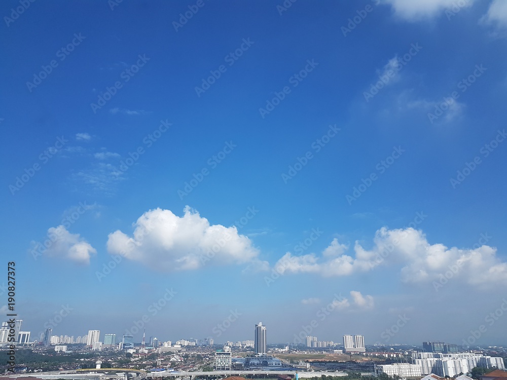 Aerial view of clear sunny day with hues of blue sky and white clouds over Johor Bahru, Malaysia's cityscape