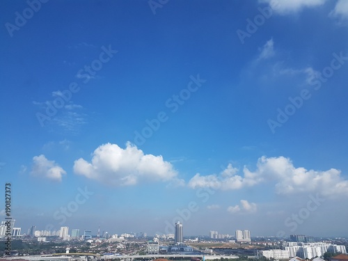 Aerial view of clear sunny day with hues of blue sky and white clouds over Johor Bahru, Malaysia's cityscape