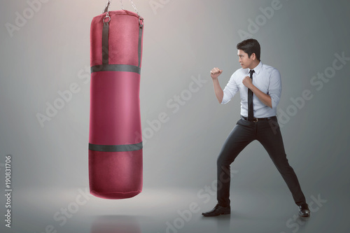 Young asian businessman punching boxing bag photo