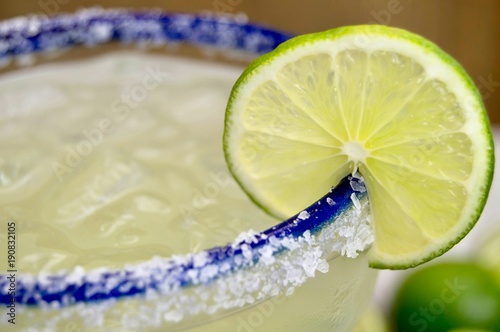 Close up of a salted, blue rimmed margarita glass with lime slice photo