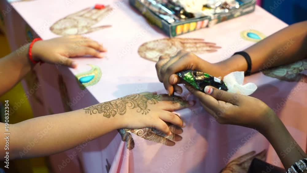 Indian woman drawing a traditional tattoo on a customer Indian woman drawing a traditional tattoo on a customer