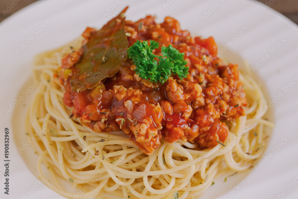 Spaghetti bolognese sauce with beef or pork,cheese,tomatoes and spices on white plate on wood table, top view with close up. Homemade delicious Italian traditional food for lunch or dinner. Spaghetti bolognese sauce with beef or pork,cheese,tomatoes and spices on white plate on wood table, top view with close up. Homemade delicious Italian traditional food for lunch or dinner.