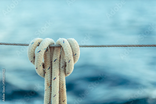 The rope knot on a steel cable on background of ocean.