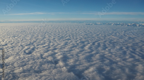 Landscape from the airplane window to a massive sea of clouds in a blue sky