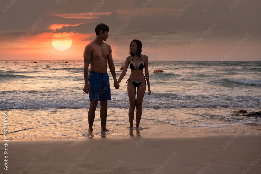 Asian couple hand in hand on the sunset beach