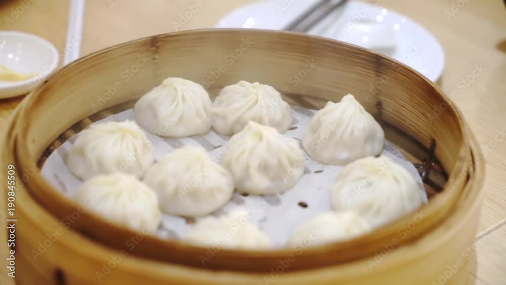 Closeup of chinese steamed dim sum served with a bamboo container on the table in the restaurant Closeup of chinese steamed dim sum served with a bamboo container on the table in the restaurant