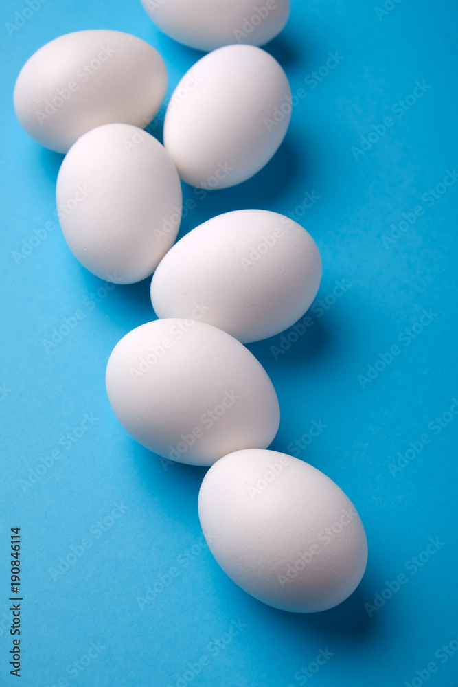 Fresh white eggs over blue background, top view. Fresh white eggs over blue background, top view.