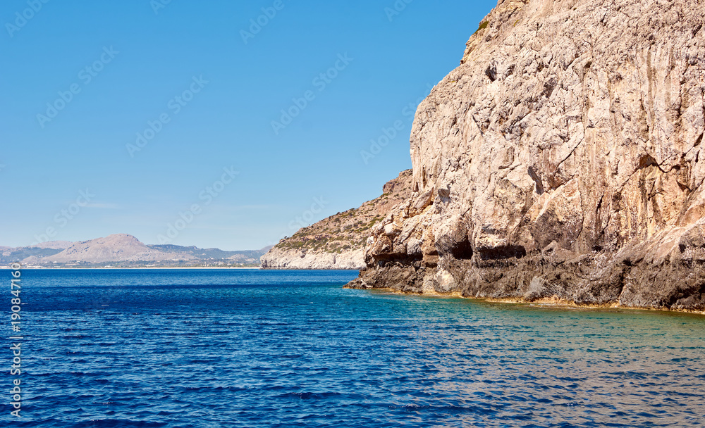 Coastal cliffs. Deep blue sea water. Coast of the Mediterranean Sea. Rhodes, Greece. Coastal cliffs. Deep blue sea water. Coast of the Mediterranean Sea. Rhodes, Greece.