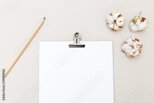 White sheet for writing with pencil and cotton flowers on a gray background. Mock up photo