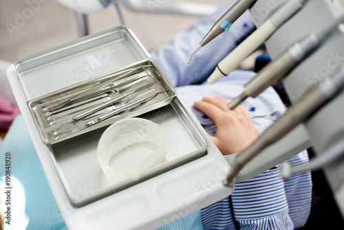Dental instruments are being displayed on a silver medical tray in a dental office.