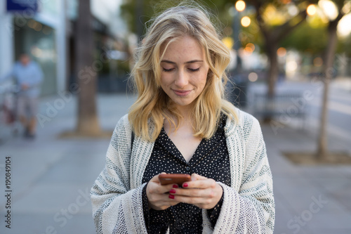 Young caucasian woman walking texting on cell phone