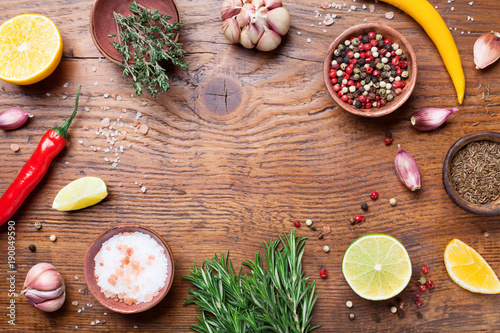 Mixed spices and fresh rosemary on wooden kitchen table top view. Ingredients for cooking. Food background.