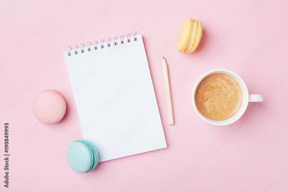 Notebook, cup of coffee and colorful macaron on pastel pink desk top view. Cozy morning breakfast. Fashion flat lay. Sweet macaroons. Notebook, cup of coffee and colorful macaron on pastel pink desk top view. Cozy morning breakfast. Fashion flat lay. Sweet macaroons.