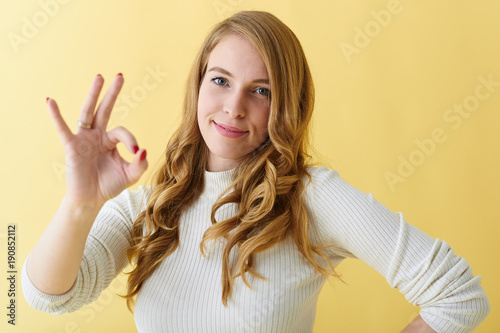 Everything is great. Positive emotions, signs and body language. Attractive friendly looking young lady smiling joyfully and making ok gesture, approving good idea or liking delicious dinner