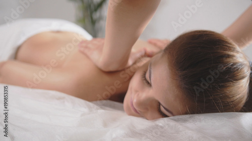 Young woman model receiving relaxing massage in spa room