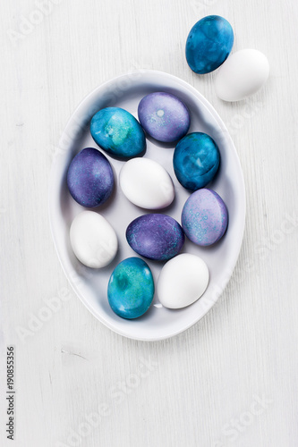Lilac, violet, white and blue Easter eggs in the plate
