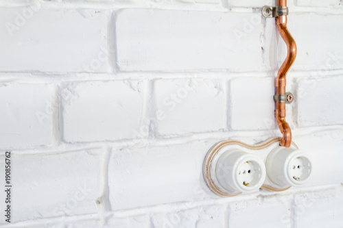 A vintage outlet and electrical wiring in a copper tube. photo
