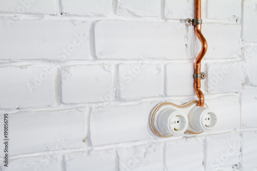 A vintage outlet and electrical wiring in a copper tube. photo