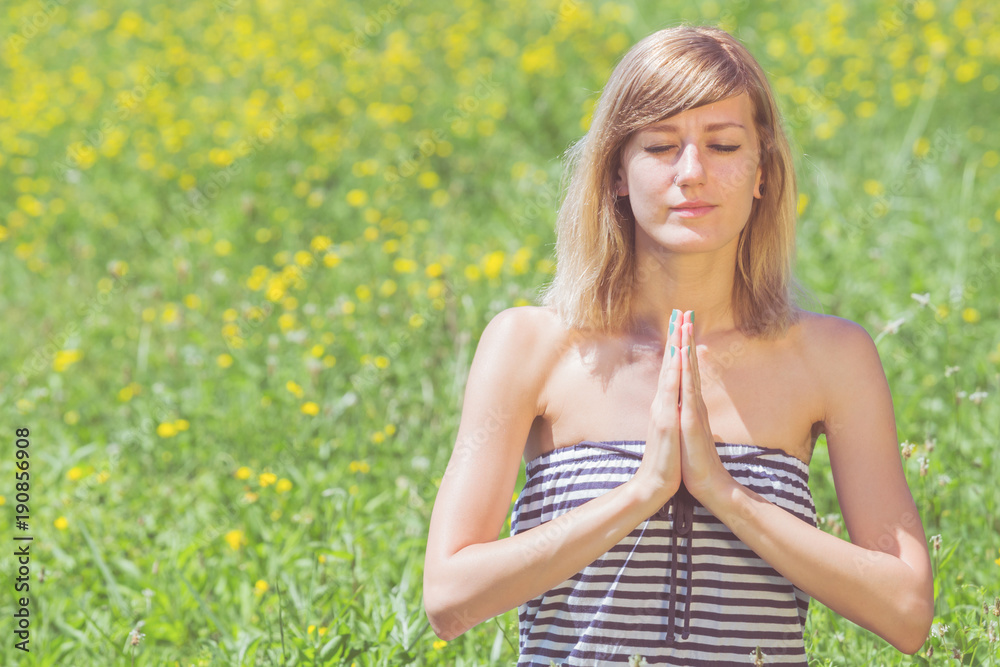 Young woman doing yoga on a flowerly meadow. Young woman doing yoga on a flowerly meadow.