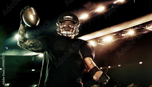 Sport concept. American football sportsman player holding ball on stadium.