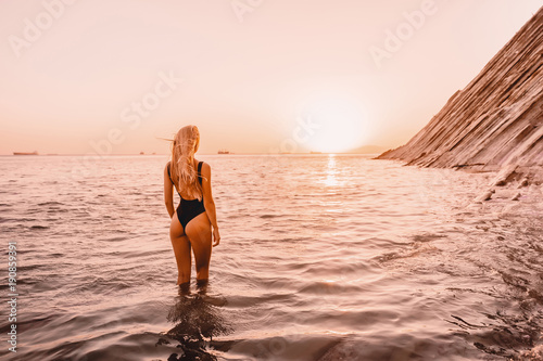 Blonde attractive woman in swimwear bikini with sunset colors.