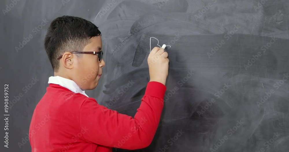 Asian student wearing uniform with glasses writing on a blackboard Asian student wearing uniform with glasses writing on a blackboard
