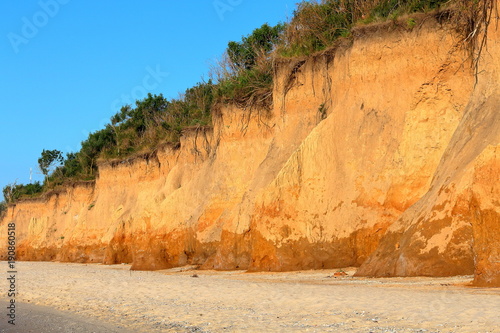 Red loamy rock (cliff of the orange clay) and sandy sea beach