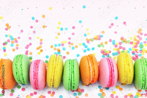Colorful macarons on bright festive decor background, selective focus, toned