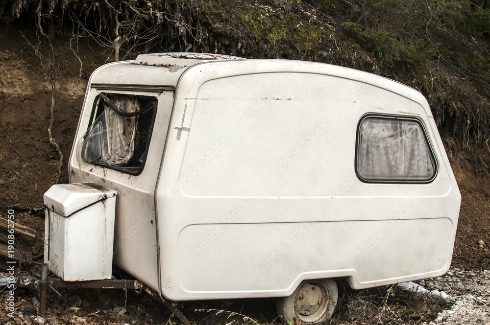 Old abandoned weathered small white vintage caravan