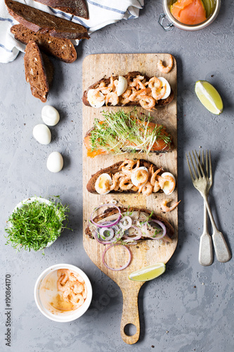 Open sandwiches with herring and onions, salmon, shrimps with rye bread, vertical, selective focus
