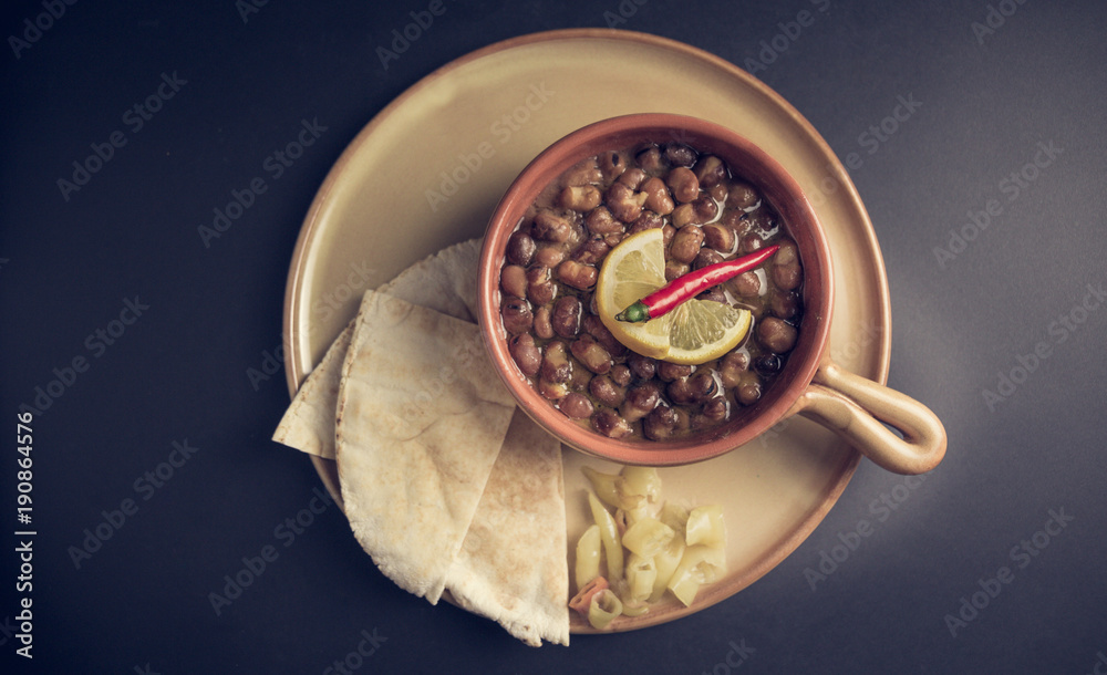 A high angle view/color image of Egyptian, Arabian, Middle Eastern Traditional food (Fava Beans with Lemon and Chili Red Paprika) A.K.A (Foul) - Also served in Lebanon, Iraq, Emirates and most of Arab A high angle view/color image of Egyptian, Arabian, Middle Eastern Traditional food (Fava Beans with Lemon and Chili Red Paprika) A.K.A (Foul) - Also served in Lebanon, Iraq, Emirates and most of Arab