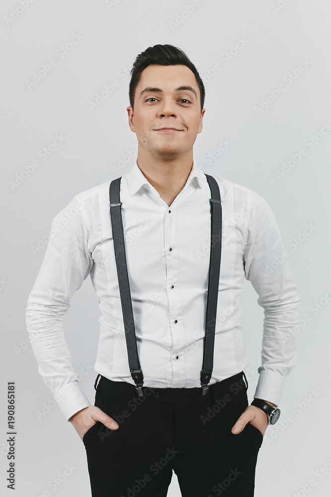 Stylish trendy young brunette man in white shirt, black pants and suspenders  on white background Stock Photo | Adobe Stock
