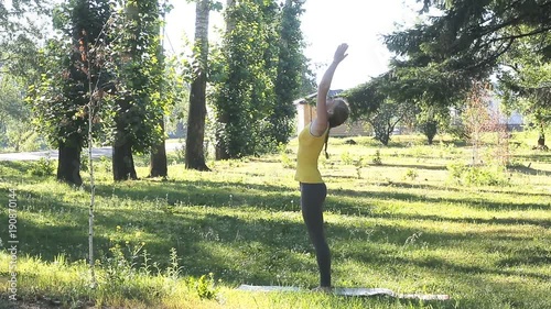 Slim woman in a park engaged in yoga exercises on the mat. Athlete takes a breath and exhale and then drill plank pose and cobra.