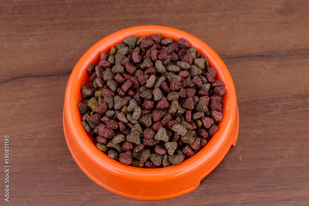 Dry cat food in bowl on wooden background. Pet food on wood surface Dry cat food in bowl on wooden background. Pet food on wood surface