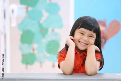 Fototapeta Asian children cute or kid girl happy fun and smile with wear red shirt on sofa
