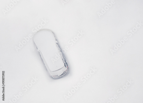 Top view on snowy car on the parkplace at the end winter. Seasonal Snowfall
