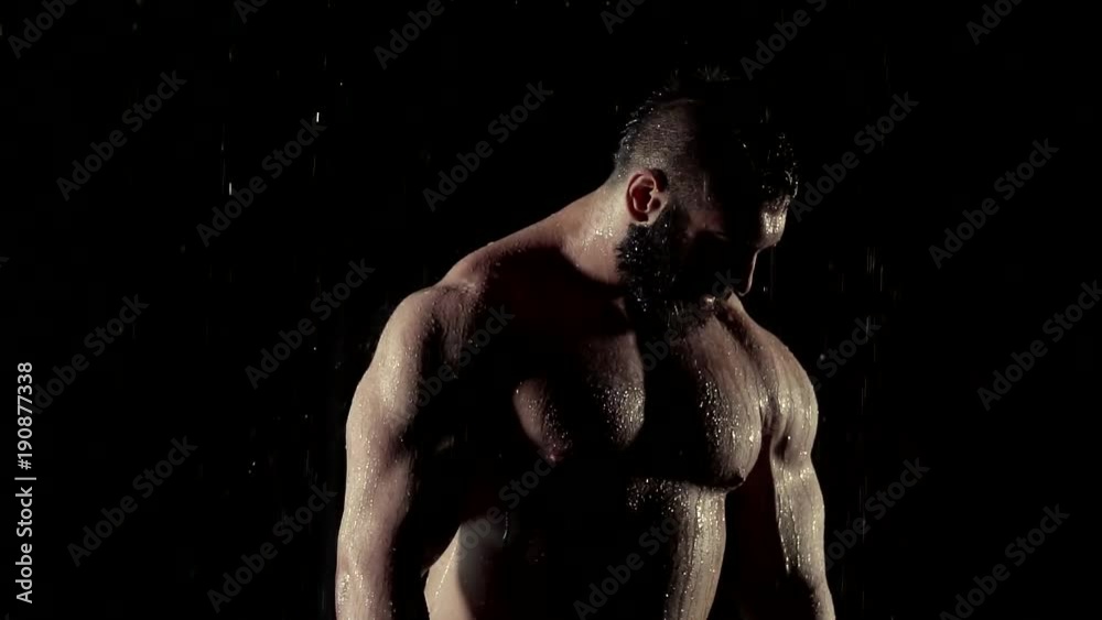 a portrait of a brutal person with an inflated torso and the muscles of the press, on whom the rain falls