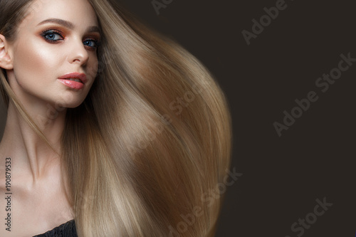 Beautiful blond girl with a perfectly smooth hair, classic make-up and red lips. Beauty face. Picture taken in the studio on a white background.