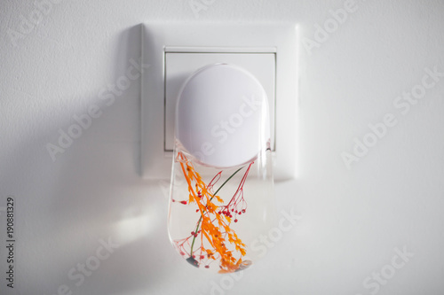Fotografie Plastic nightlight illuminating the wall and light switch.