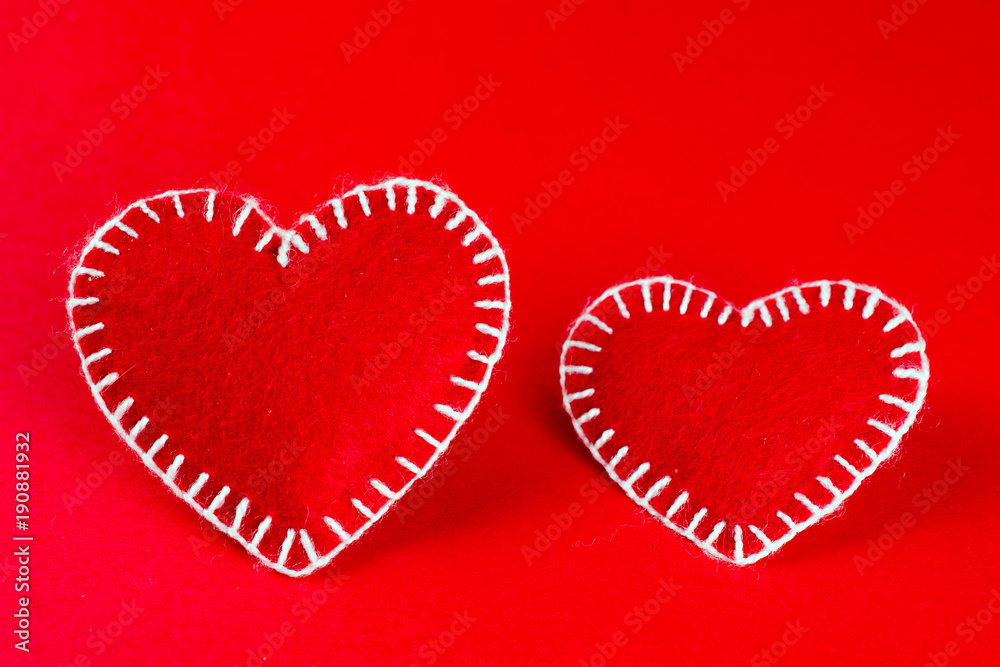 two decorative hearts made of red fumirana sewn with a white thread, on a red background. Happy Valentine's Day symbol. selective focus. close-up. can be used as a background two decorative hearts made of red fumirana sewn with a white thread, on a red background. Happy Valentine's Day symbol. selective focus. close-up. can be used as a background