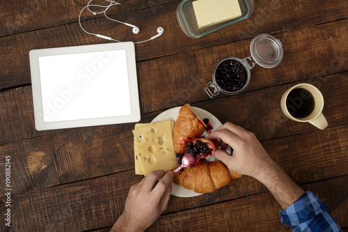 Man eats breakfast croissant, coffee, cheese at home, top view © kucherav