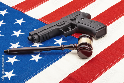 Wooden judge gavel and black color gun over US flag