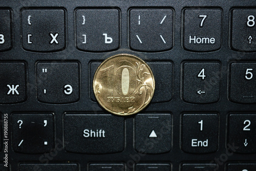 Монета в десять рублей на клавиатуре ноутбука.