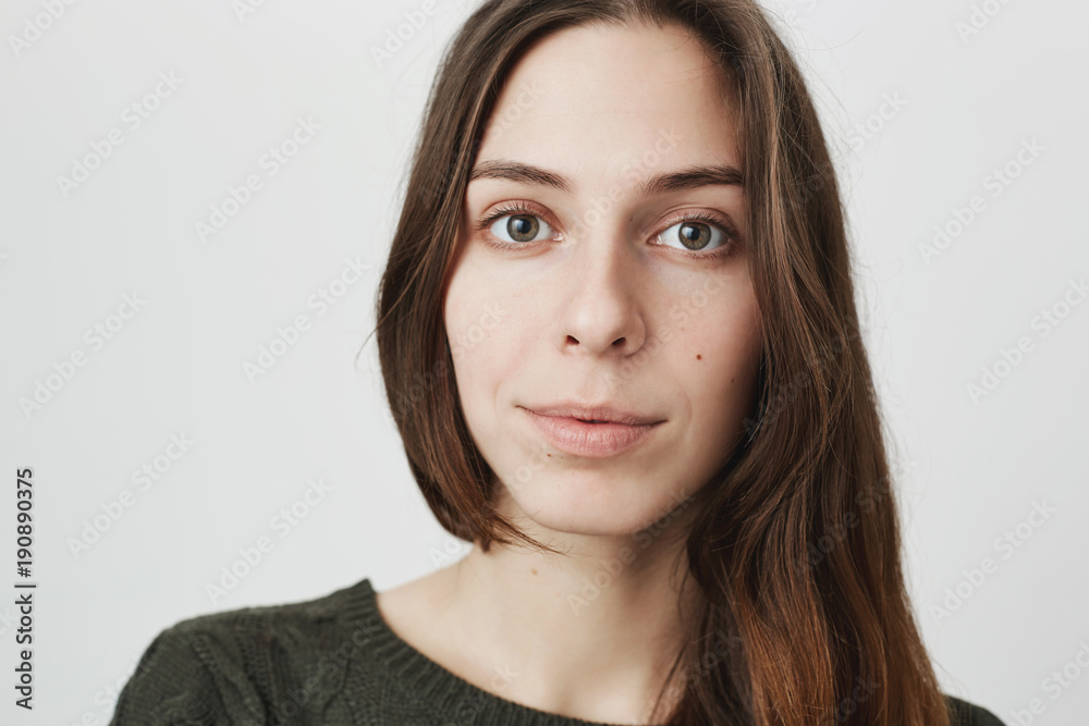 Close up portrait of attractive young female brunette with cute smile on her face expressing interest in something, isolated over white background. Beautiful student listens carefully what her Close up portrait of attractive young female brunette with cute smile on her face expressing interest in something, isolated over white background. Beautiful student listens carefully what her