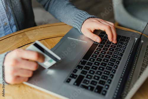 Male hands holding credit card and using laptop. Online shopping concept
