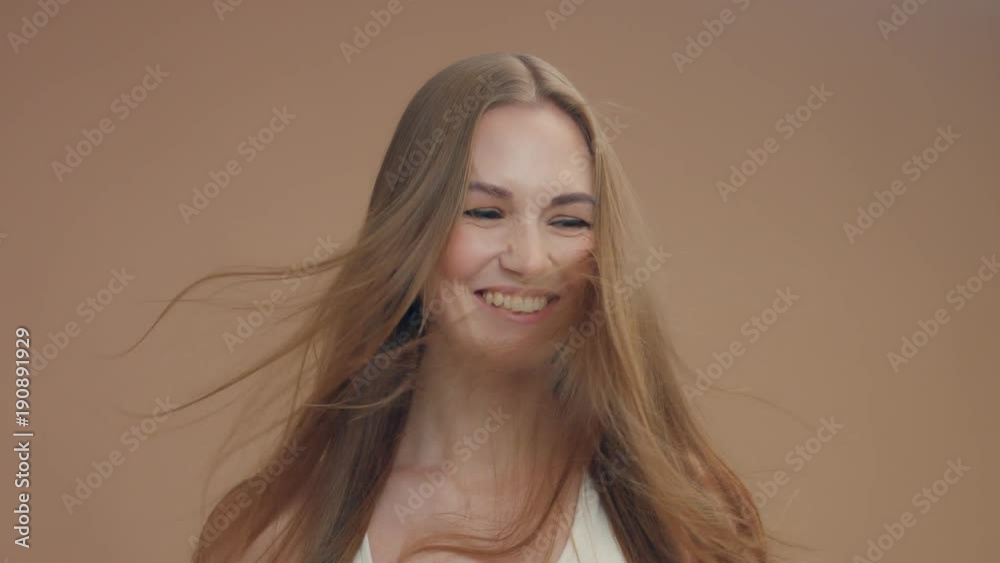 beauty woman model in studio on beige background with wind in hair bllowing it. white top beauty woman model in studio on beige background with wind in hair bllowing it. white top