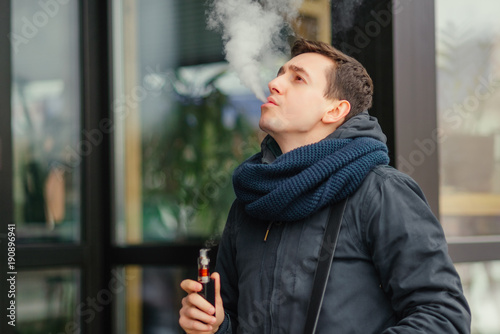 Vaping. Young men vaping an electronic cigarette. Vaping outdoors. Safe smoking. Young vaper.