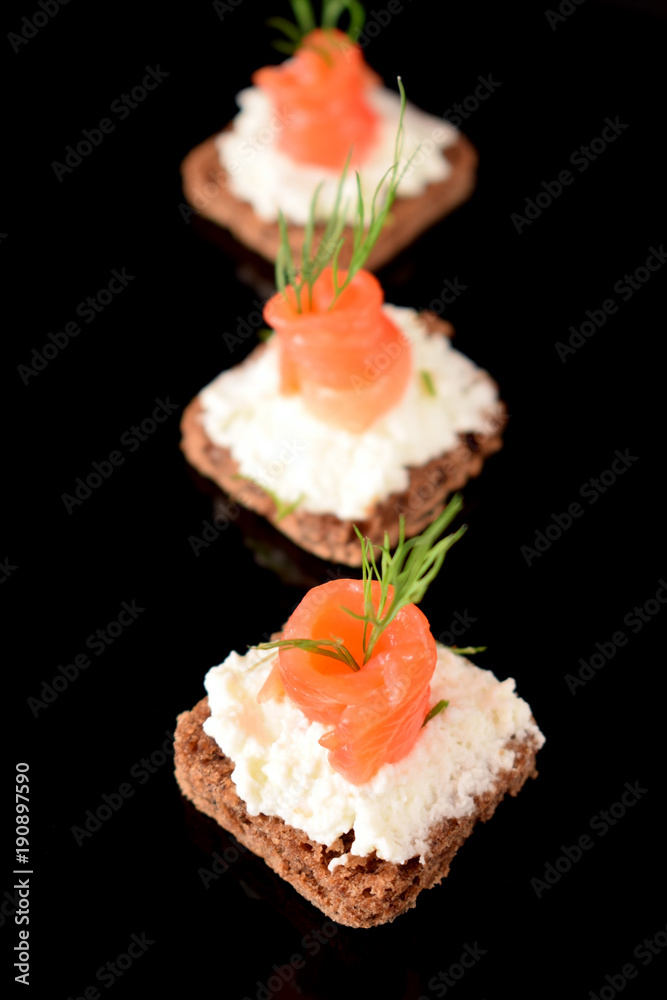 Canape with salmon and cream cheese on black background Canape with salmon and cream cheese on black background
