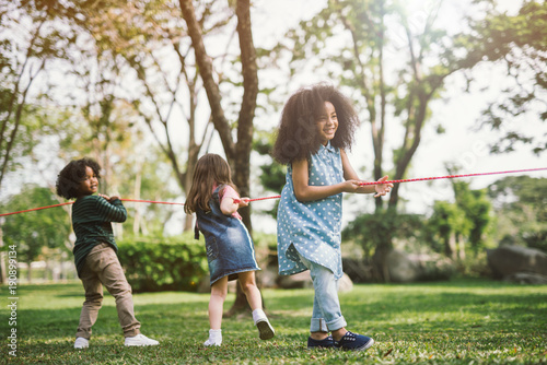 Happy children playing tug of war at the park